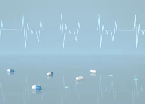 Capsules scattered on a reflective surface with an ECG line, symbolizing medicine and his alchemy in healing.